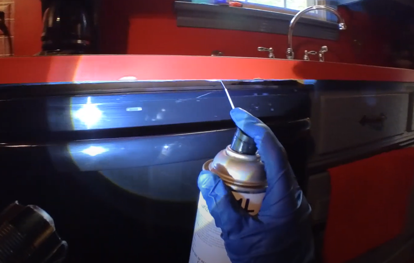 Technician spraying insecticide under a kitchen counter — Pest Control Service in Davis targeting hidden pests.