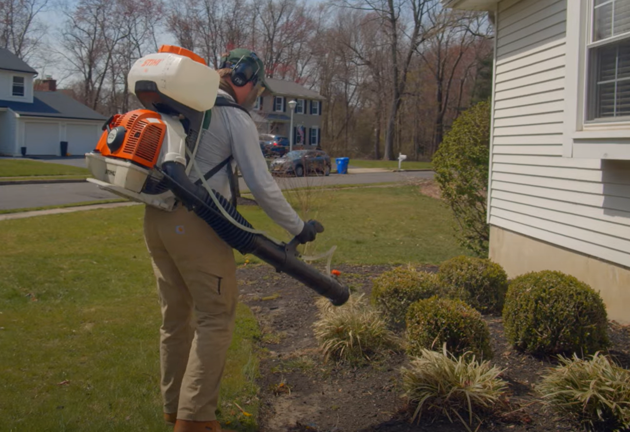 Professional exterminator using a backpack sprayer around a home’s yard — Pest Control Service in Davis for outdoor mosquito and insect control.