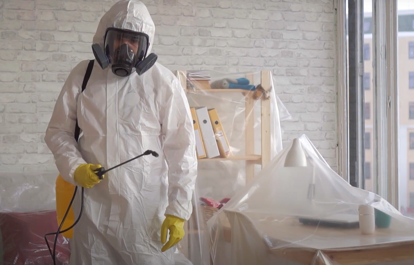 Pest control specialist in hazmat suit spraying inside a home — Pest Control Service in Davis for safe fumigation services.